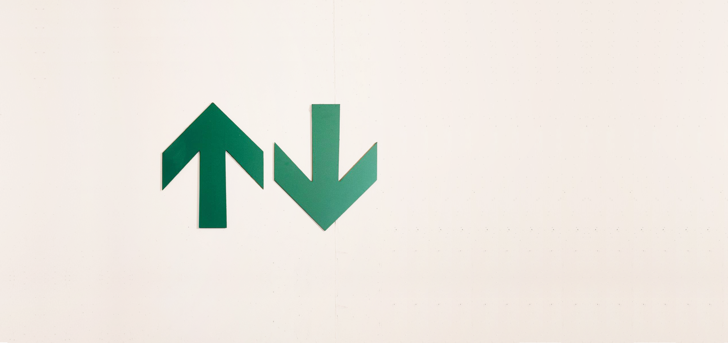 Zwei grüne Pfeile auf einer Betonwand zeigen nach oben bzw. nach unten