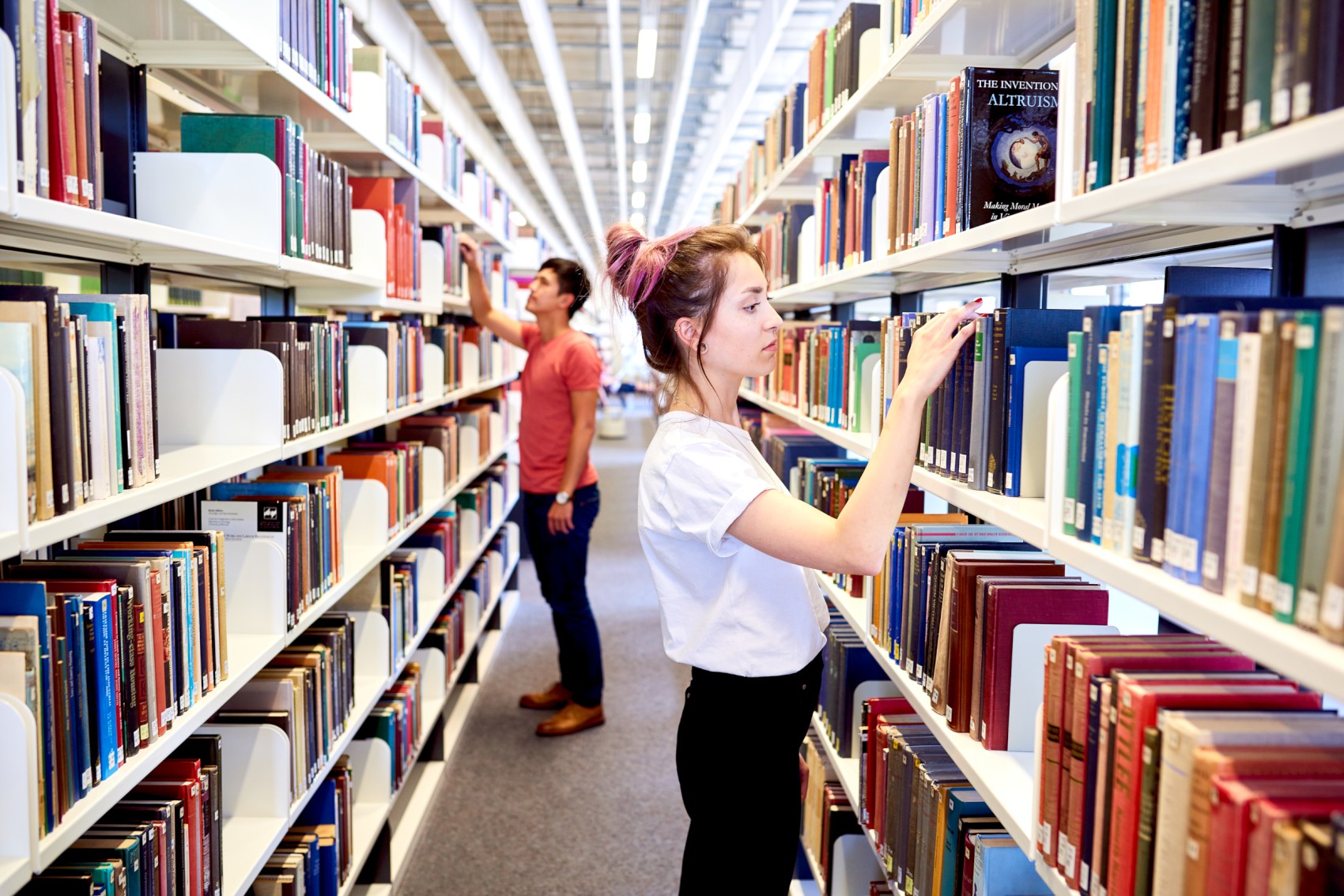 Two students looking for books at the library