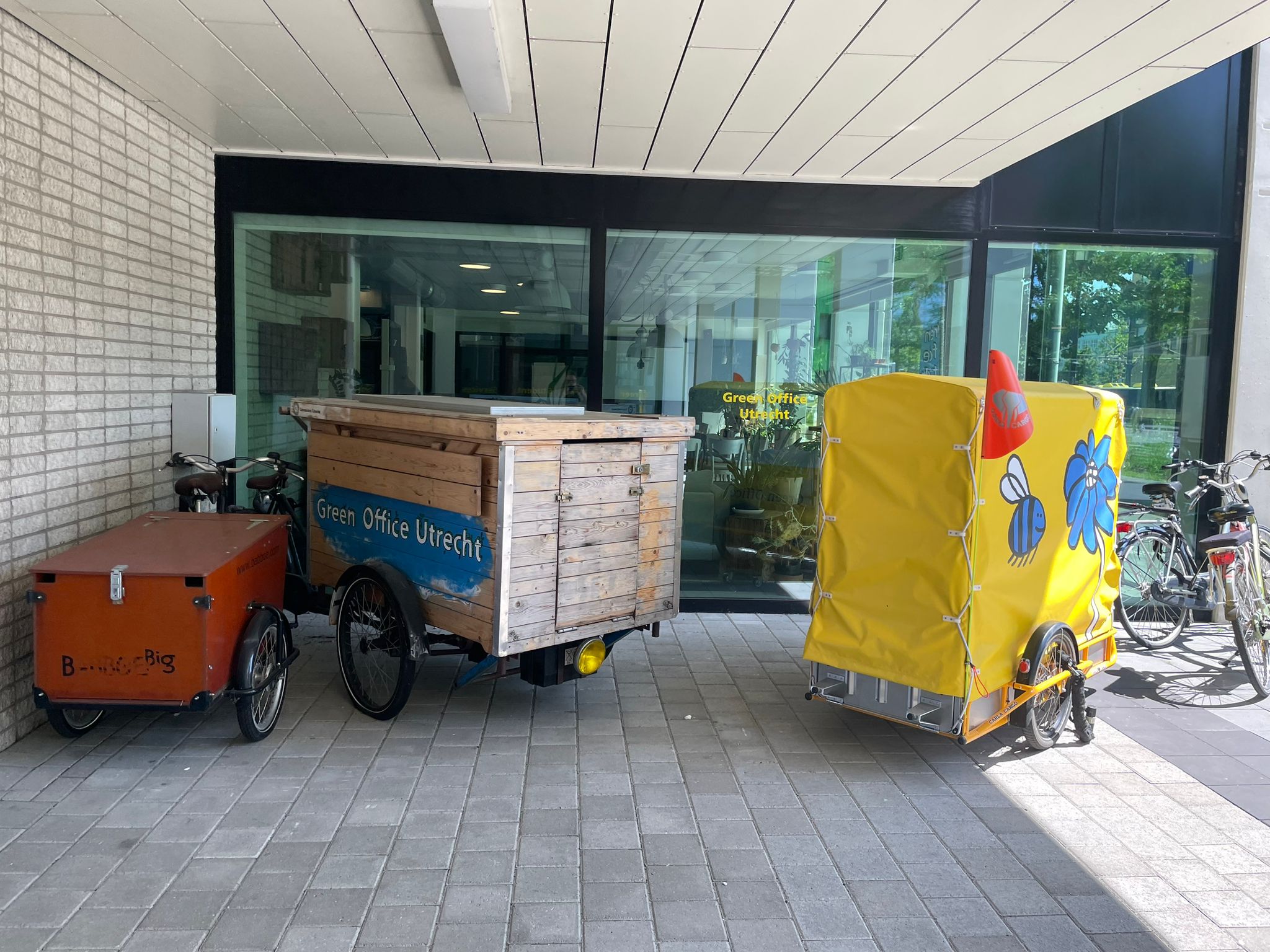 Drei unterschiedliche Lastenräder, teilweise mit sehr großen Transportboxen, stehen vor dem Green Office zur kostenlosen Ausleihe bereit